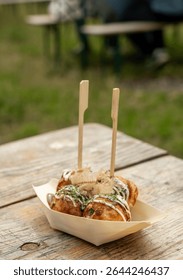 Takoyaki - traditional Japanese street food, outdoor snack with octopus Takoyaki fried balls, delicious squid dumplings on wood table