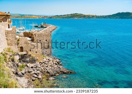 Talamone rocky beach and medieval fortress Rocca Aldobrandesca and walls. The village lies on a rocky promontory, in Maremma nature reserve, mount Argentario, Tuscany, Italy