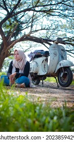 Talang , Indonesia - June 25 , 2021
Young Woman In Hijab Relaxing Under The Tree With Her Vespa