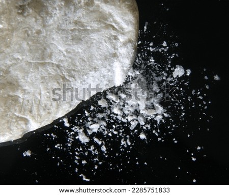 Talc sample being crushed into powder against a black background