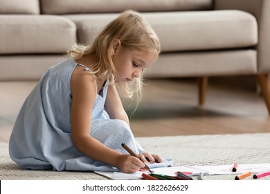 Talented artist  Inspired attentive little preschool child girl sitting warm floor in cozy apartment painting funny pictures and fiber  tip pens  drawing bright imaginary world piece paper