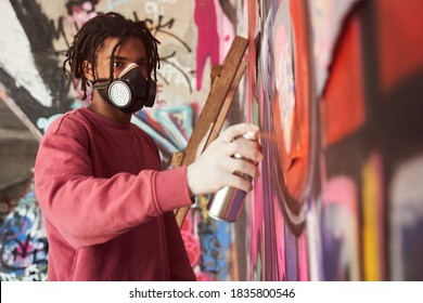 Talented artist. Street artist painting colored graffiti while standing at the stepladder and pulverizing spray paint can at the big huge wall. Urban, street art, millennials generation, mural concept