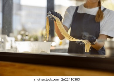 A talented chef skillfully pulls freshly made pasta, beautifully showcasing culinary artistry in a modern setting