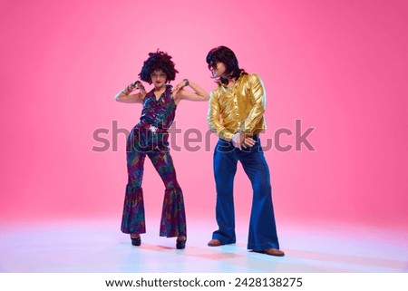 Talented dancers, man and woman in retro style outfits posing against gradient pink studio background. Concept of American culture, 1970s, 1980s fashion, music, comparisons of eras.