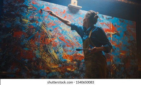 Talented Female Artist Energetically and Enthusiastically Using Paint Brush She Creates Modern Masterpiece of the Oil Painting. Creative Studio with Large Canvas of Striking Colors. Low Angle Shot