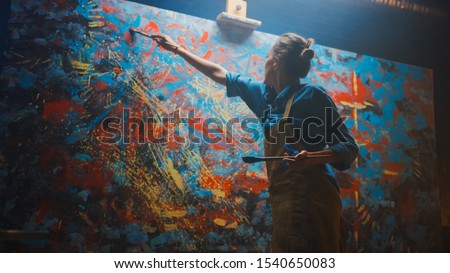 Talented Female Artist Energetically and Enthusiastically Using Paint Brush She Creates Modern Masterpiece of the Oil Painting. Creative Studio with Large Canvas of Striking Colors. Low Angle Shot