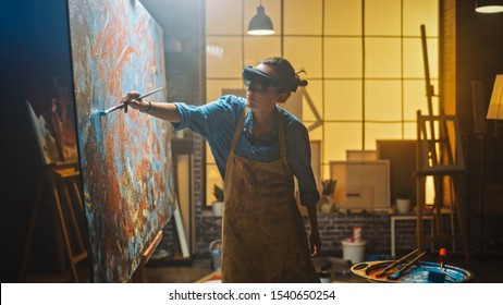 Talented Female Artist Wearing Augmented Reality Headset Working on Abstract Painting, Uses Paint Brush To Create New Concept Art Using Virtual Reality Interface. High tech Creative Modern Studio