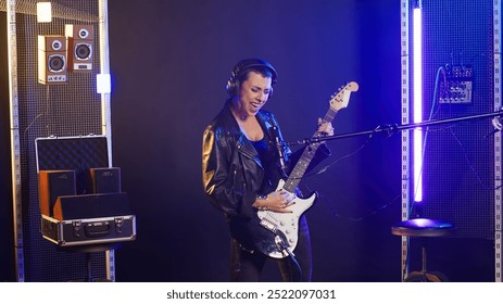 Talented female guitarist delivers a powerful music performance in a dark urban studio. Musical artist with grunge style and cool energy making her a superstar performer. Heavy metal. Camera B. - Powered by Shutterstock