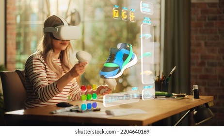 Talented Female Shoes Designer Wearing Virtual Reality Headset and Using Controllers to Design a Fashionable Sneaker in Augmented Reality Software. Woman Working on Digital Footwear at Home. - Powered by Shutterstock