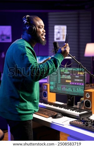 Talented performer singer does a recording session for his acoustic song, performing on microphone in home studio. Confident artist musician working on producing new track records.