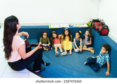 Talented Preschool Teacher Playing The Guitar And Singing An Education Song For Her Kindergarten Students At A Music Lesson