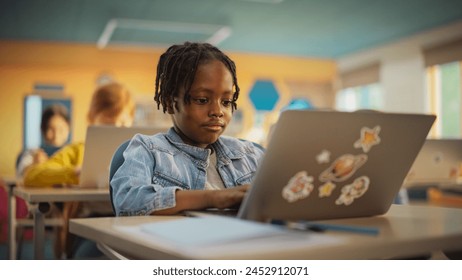 Talented Small African American Boy Using a Laptop Computer in Class. Portrait of a Happy Elementary School Student Studying Hard, Learning New Things, Getting Modern Education Online - Powered by Shutterstock