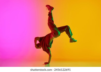 Talented solo artist, male break-dancer performing hip-hop in neon light against gradient pink-yellow background. Concept of art, hobby, sport, creativity, fashion and style, action. Ad - Powered by Shutterstock