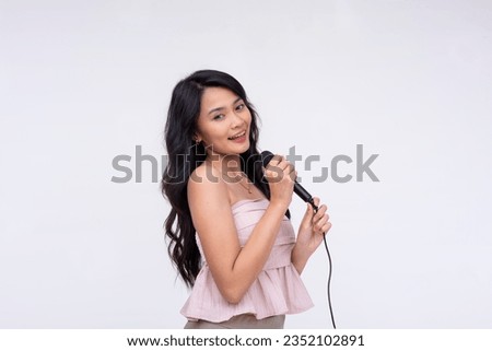 A talented young asian vocalist singing on the microphone. A pretty lady doing karaoke and having fun. Isolated on a white background.