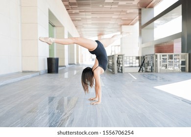 Talented young ballerina doing splits while balancing on hands in urban scene - Powered by Shutterstock