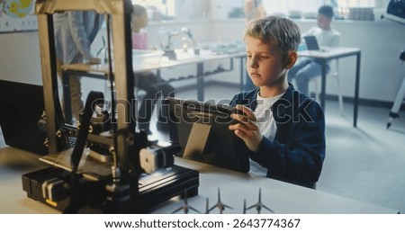 Talented Young Boy Sitting at Table, Writing Code for Advanced Automated 3D Printer on Digital Tablet. Primary School Student Learning Programming in Multiethnic Classroom. Interactive STEM Education.