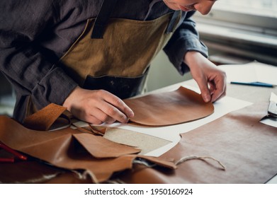 A talented young guy helps his father in the family business, cuts out blanks for shoes from leather - Powered by Shutterstock