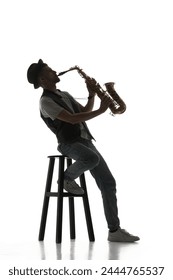 Talented young man making creative performance, playing saxophone isolate don white background. Black and white image. Concept of music, festival, concert, entertainment, instruments. Poster, ad