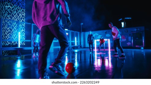 Talented Young Soccer Player Skilfully Dribbling Ball During a Street Football Game with Friends. Handsome Footballer Scoring a Winning Goal. Playing at Night with Neon Lights After Rain - Powered by Shutterstock