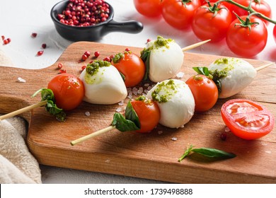 talian food - caprese salad - skewer with tomato, mozzarella and basil, pesto sauce, mediterranean diet concept on old chopping board and linen cloth close up - Powered by Shutterstock