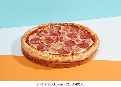 talian pizza with salami, ham, bacon, pepperoni on coloured background. Meat pizza with sausage and bacon in minimal style on blue, orange color. American pizza delivery concept with color backdrop - Shutterstock ID 2155040145