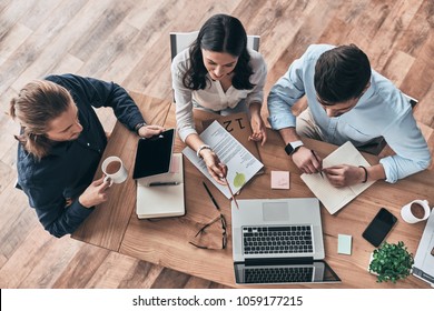 Talking About Business Details. Top View Of Young Modern Colleagues In Smart Casual Wear Working Together While Spending Time In The Office