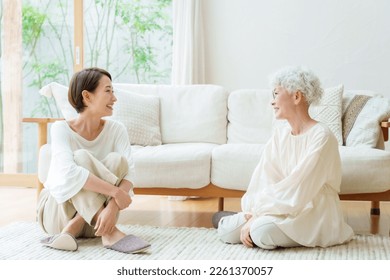 talking asian mother and daughter sitting on floor in a living room