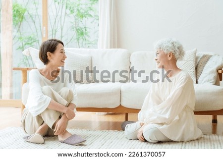 talking asian mother and daughter sitting on floor in a living room