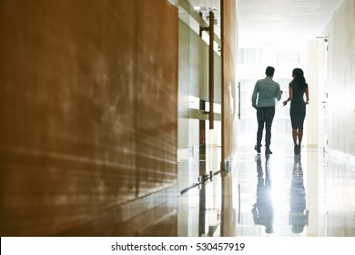 Talking Coworkers Walking Along Corridor In Office