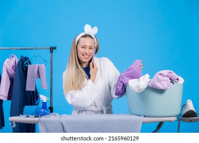 Talking On The Phone With A Friend While Getting Ready For Work In The Morning. A Smiling Girl Wearing A Robe And A Headband Is Sorting Clothes, Ironing Them.