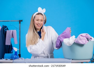 Talking On The Phone With A Friend While Getting Ready For Work In The Morning. A Smiling Girl Wearing A Robe And A Headband Is Sorting Clothes, Ironing Them.