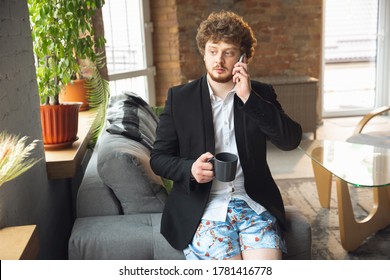 Talking On Phone. Man Without Pants But In Jacket Working On A Computer, Laptop. Remote Office During Coronavirus, Fun And Comfortable In Underpants. Insulation, Quarantine, Humor, Business Concept.