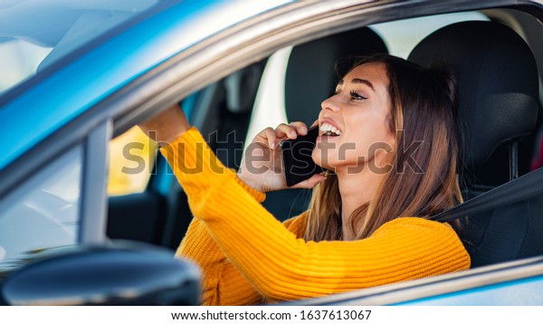 Talking on\
the phone while driving. Texting and driving. Distracted driver\
behind the wheel. Beautiful female Driver talking on the Phone.\
Young woman talking on phone while driving\
car