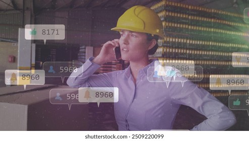 Talking on phone, woman in hard hat with social media notifications image over warehouse. Business, communication, logistics, technology, safety, industrial - Powered by Shutterstock