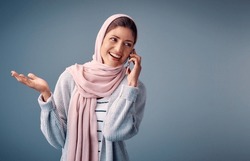 Talking, Phone Call And Muslim Woman With Smartphone In Studio For Conversation, Networking Or Gossip On Blue Background. Contact, Happy And Arab Person With For Chatting, Speaking Or Discussion