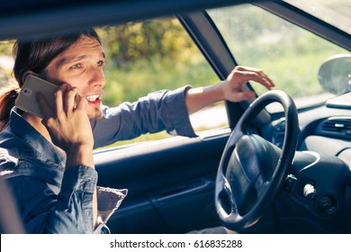 Talking while drive, danger fresh driver concept. Young man driving car using his smartphone, talking with someone. - Shutterstock ID 616835288