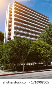 Tall apartment building in the suburbs with trees - Residential Rentals - Commercial Real Estate Investment - Shutterstock ID 1716909505