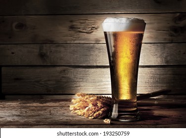 Tall Beer Glass With Beer And Ears On Wooden Background