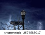 a tall black metal lamp post with street signs surrounded by bare winter trees with powerful storm clouds and lightning in the Marietta Square in Marietta Georgia USA	