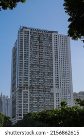 A Tall Building In Jakarta With Shades Of Clear Sky And Green Trees