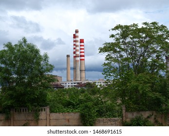 Tall Chimneys Of An Old Coal Plant, Surrounded By Lush Vegetation