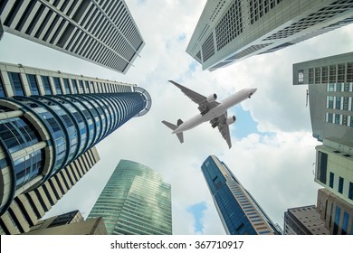 Tall city buildings and a plane flying overhead in morning at Singapore