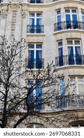 Tall elegant building facade featuring multiple stories, decorative stone carvings, traditional windows, and wrought iron balconies. Antwerp, Belgium