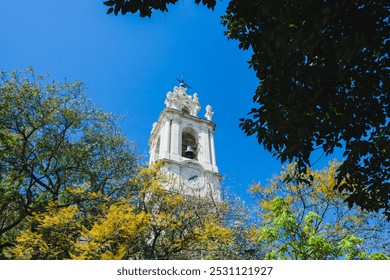 a tall, elegant white clock tower with intricate architectural details, likely part of a church or historical building. - Powered by Shutterstock