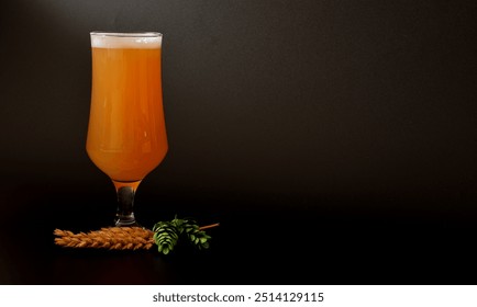 A tall glass of wheat light beer with foam on a black background, next to ears and ripe hop fruits. Close-up. - Powered by Shutterstock