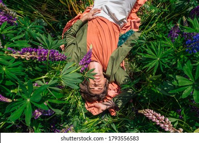 Tall handsome man in a green jacket lying among the lupines flowers. Top view.