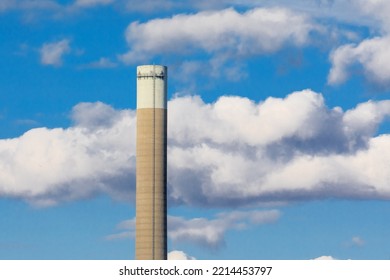 A Tall Industrial Smoke Stack Against A Cloudy Sky