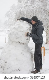 Tall Man Making Really Tall Snowman While Massive Snow Storm