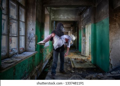 A Tall Man In A Plague Doctor's Suit Is Holding A Woman With A Bandaged Face And A Knife In Her Hand. Monsters From Comics Or Horror Films, An Epic Scene.