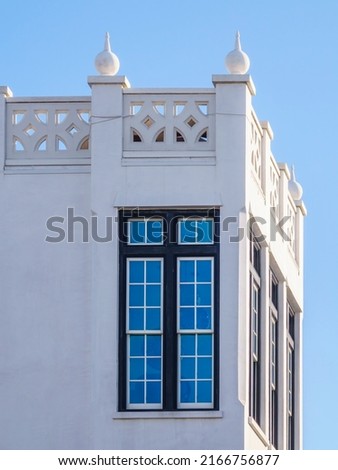 Tall narrow windows near decorative top corner of whitewashed concrete house in New Urbanist architectural style in a beach town on a sunny afternoon along the Gulf Coast in northwest Florida